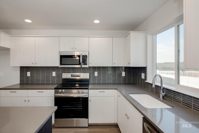 kitchen featuring tasteful backsplash, appliances with stainless steel finishes, sink, and white cabinets