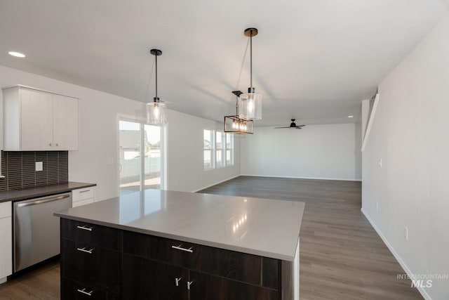 kitchen featuring a kitchen island, pendant lighting, decorative backsplash, hardwood / wood-style flooring, and stainless steel dishwasher