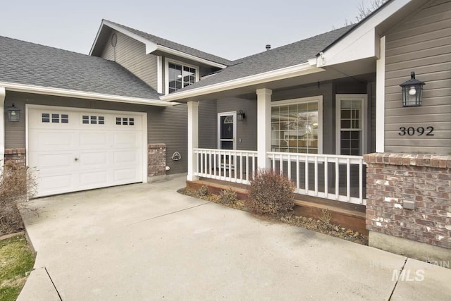 doorway to property featuring an attached garage, a shingled roof, a porch, and concrete driveway