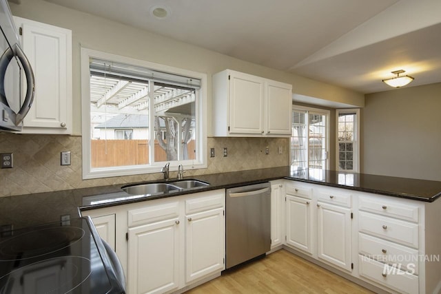 kitchen featuring a peninsula, a sink, white cabinets, black appliances, and dark countertops