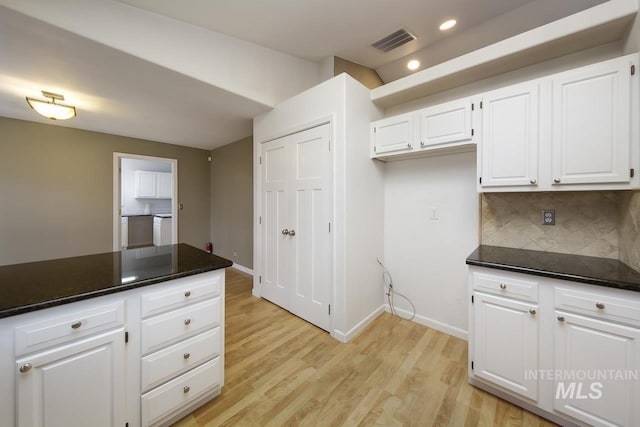 kitchen featuring visible vents, white cabinetry, backsplash, light wood finished floors, and dark countertops