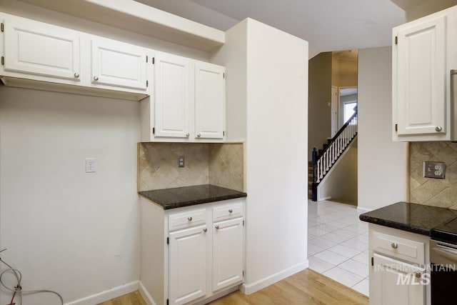 kitchen with light wood-type flooring, tasteful backsplash, baseboards, and white cabinets