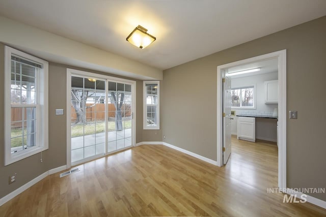 unfurnished dining area featuring light wood-style flooring, visible vents, and baseboards