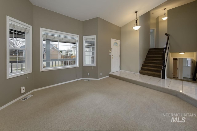 carpeted entryway with baseboards, visible vents, stairway, tile patterned flooring, and high vaulted ceiling