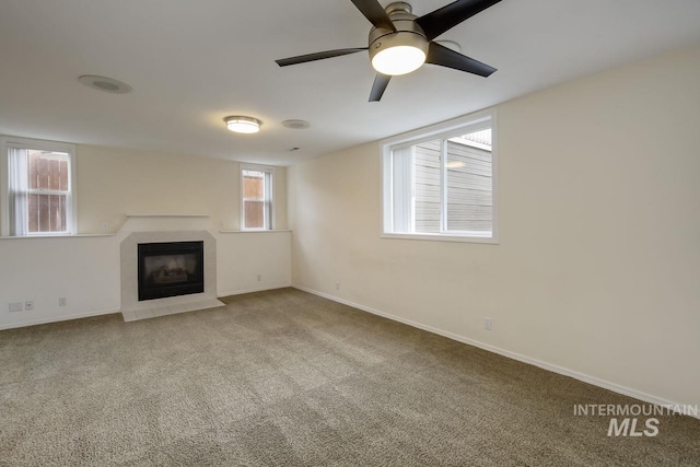 unfurnished living room featuring a tile fireplace, carpet flooring, a ceiling fan, and baseboards