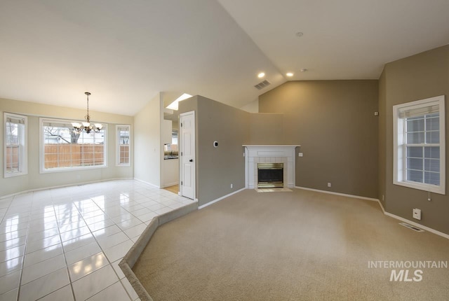 unfurnished living room with lofted ceiling, light tile patterned floors, visible vents, and a tiled fireplace