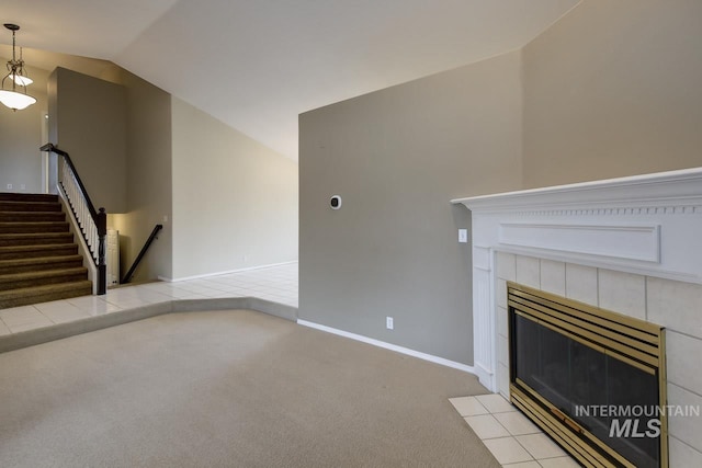 unfurnished living room with lofted ceiling, a tile fireplace, carpet flooring, baseboards, and stairway