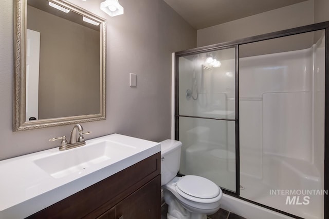 bathroom featuring a shower stall, toilet, and vanity