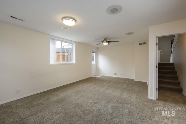 carpeted spare room with a ceiling fan, visible vents, stairway, and baseboards