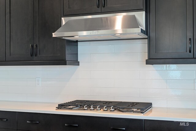 kitchen with light countertops, stainless steel gas cooktop, under cabinet range hood, and decorative backsplash