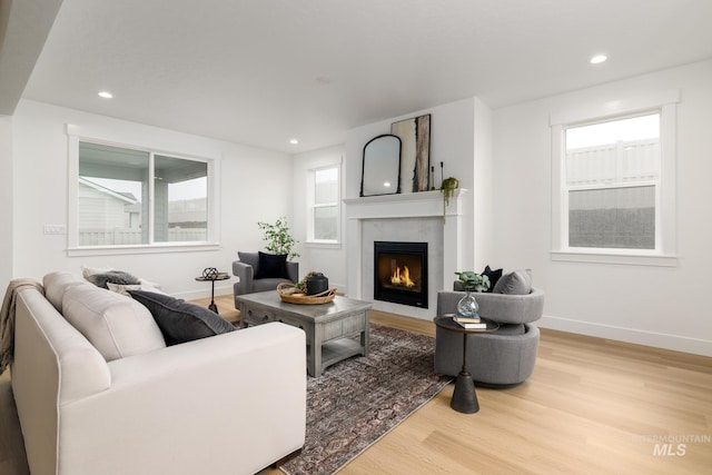 living room featuring a large fireplace, baseboards, wood finished floors, and recessed lighting