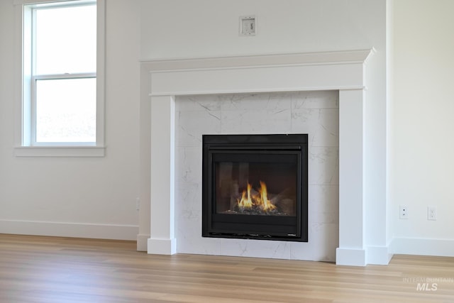 interior details featuring a tile fireplace, baseboards, and wood finished floors