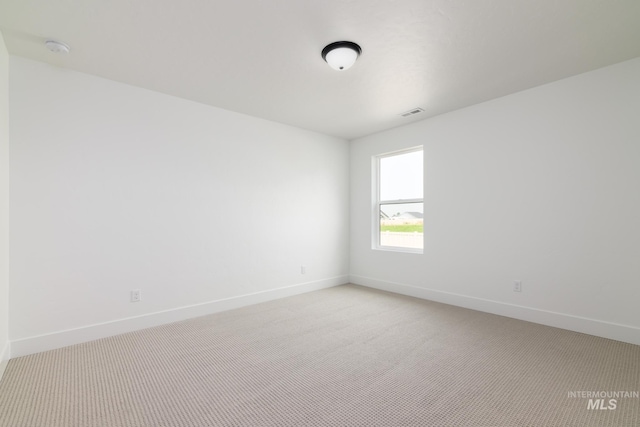 spare room featuring light carpet, visible vents, and baseboards