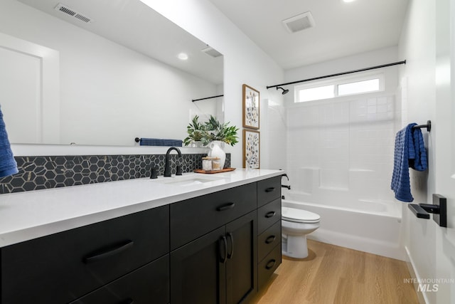 bathroom featuring visible vents, toilet, tub / shower combination, vanity, and wood finished floors