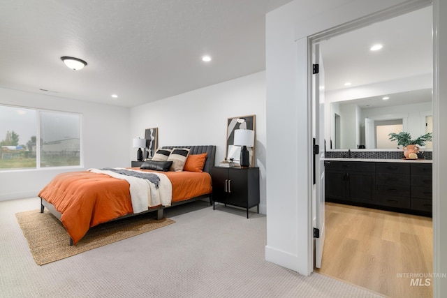 bedroom featuring recessed lighting, baseboards, light carpet, and ensuite bath