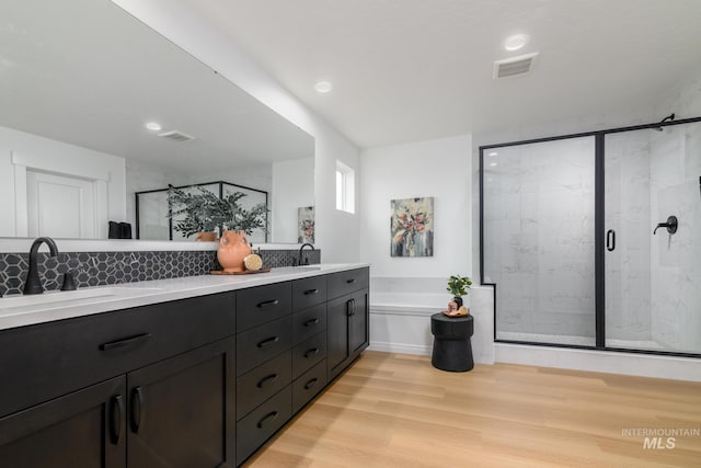 bathroom with a stall shower, visible vents, a sink, and wood finished floors