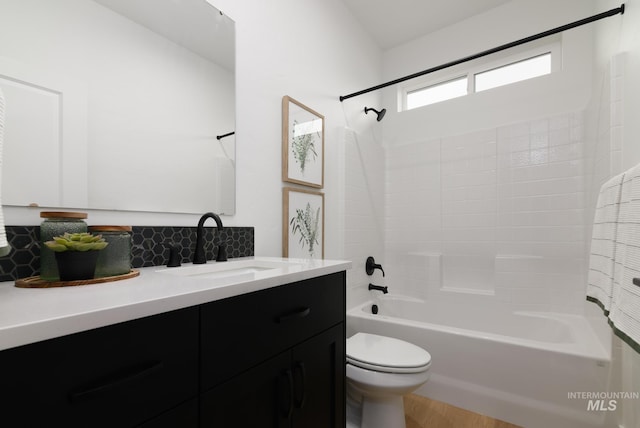 full bath featuring toilet, shower / washtub combination, vanity, and tasteful backsplash