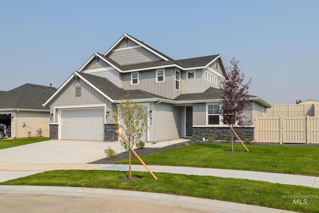 craftsman-style home featuring driveway, stone siding, fence, a front lawn, and board and batten siding