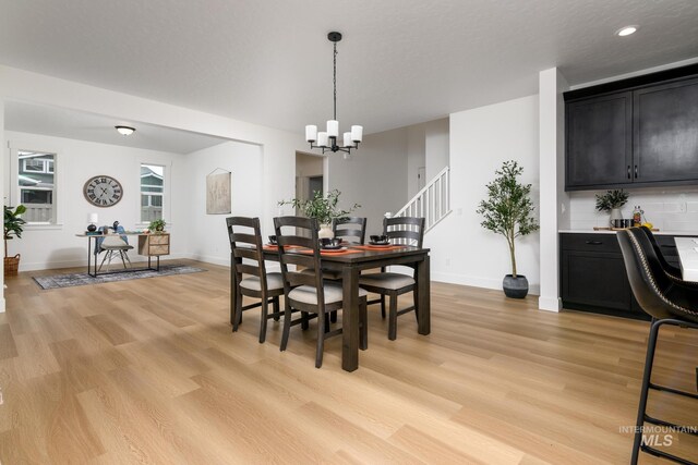 dining area with light wood finished floors, recessed lighting, stairway, an inviting chandelier, and baseboards