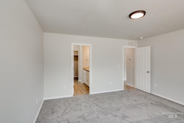 unfurnished bedroom featuring light colored carpet, a closet, connected bathroom, and a walk in closet