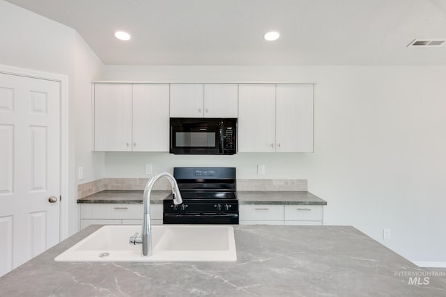 kitchen featuring sink, white cabinetry, and stove