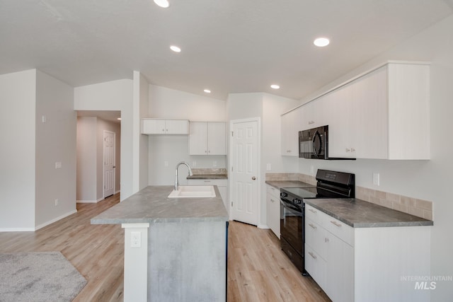 kitchen featuring white cabinets, light wood-type flooring, vaulted ceiling, and black appliances