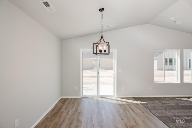 unfurnished dining area with a notable chandelier, vaulted ceiling, and hardwood / wood-style floors