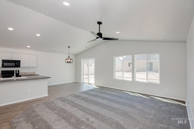 unfurnished living room with ceiling fan, lofted ceiling, dark hardwood / wood-style floors, and a healthy amount of sunlight