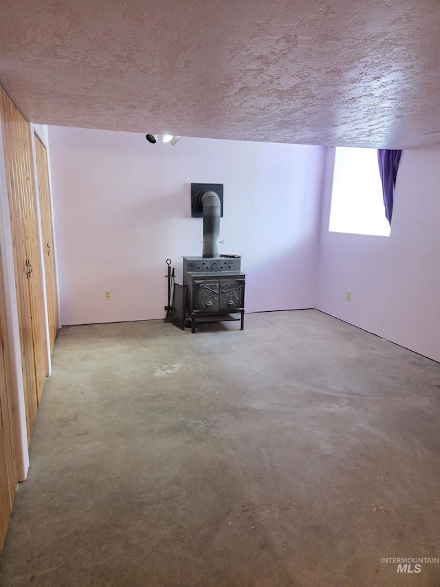 1922 9th Ave, Lewiston, ID 83501 - unfurnished living room featuring a wood stove, a textured ceiling, and concrete flooring