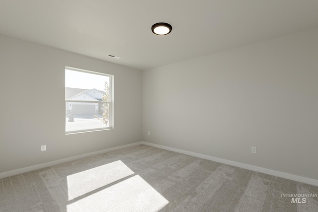 unfurnished room featuring baseboards, visible vents, and light colored carpet