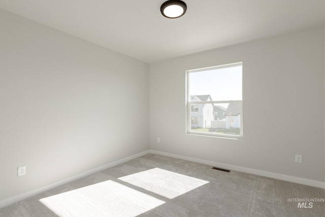 empty room featuring baseboards, visible vents, and light colored carpet