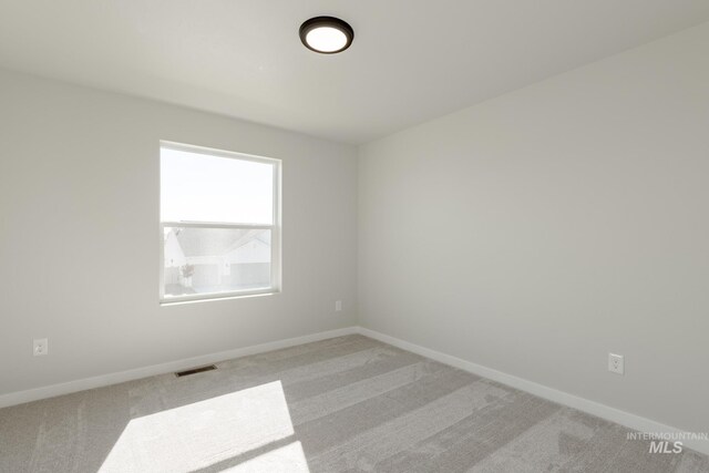 unfurnished room with light colored carpet, visible vents, and baseboards