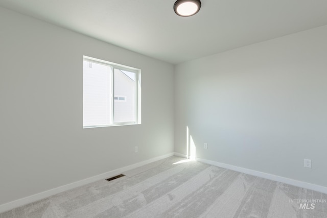 empty room featuring visible vents, light carpet, and baseboards