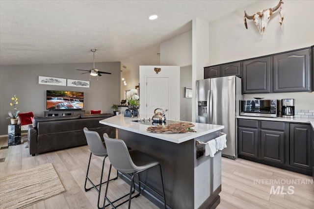 kitchen with light wood finished floors, appliances with stainless steel finishes, a breakfast bar, and light countertops