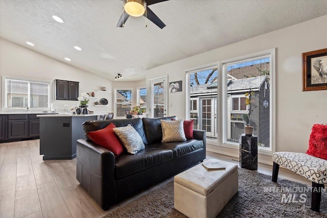 living room with lofted ceiling, recessed lighting, light wood-style flooring, a textured ceiling, and a ceiling fan