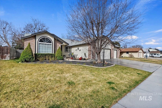 view of front facade with driveway, fence, a front yard, an attached garage, and brick siding