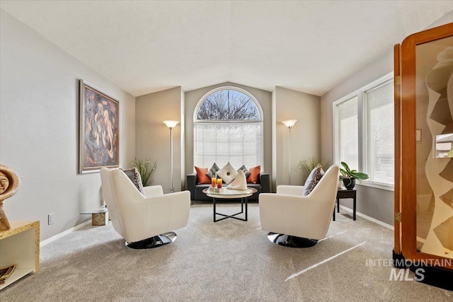 carpeted living area featuring vaulted ceiling and baseboards