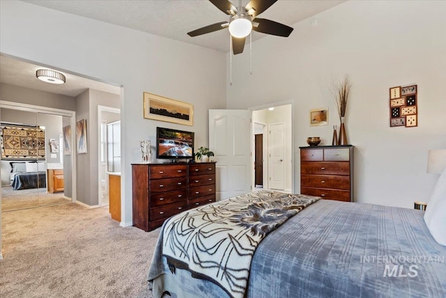 carpeted bedroom with ensuite bath, baseboards, and ceiling fan