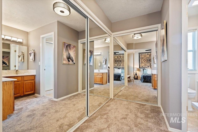 ensuite bathroom featuring toilet, vanity, and a textured ceiling