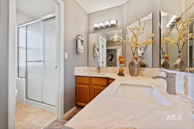 full bathroom with a sink, toilet, double vanity, and a shower stall