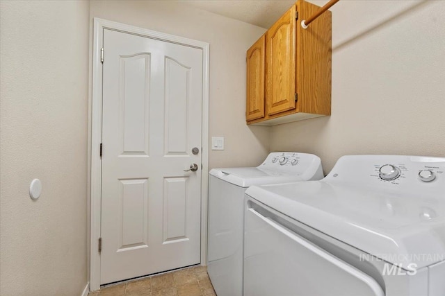 clothes washing area featuring cabinet space and washer and clothes dryer