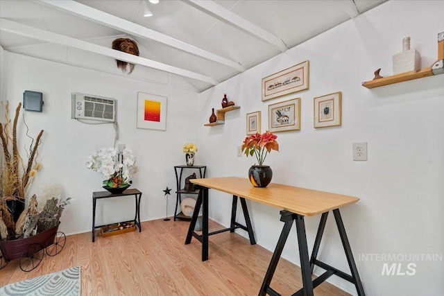 office area with a wall unit AC, vaulted ceiling with beams, and light wood finished floors