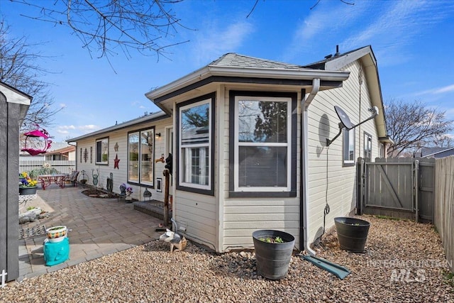 view of side of property with a patio area, a fenced backyard, and a gate