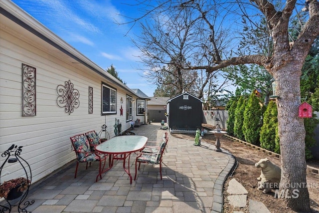 view of patio / terrace with an outdoor structure, fence, and a shed