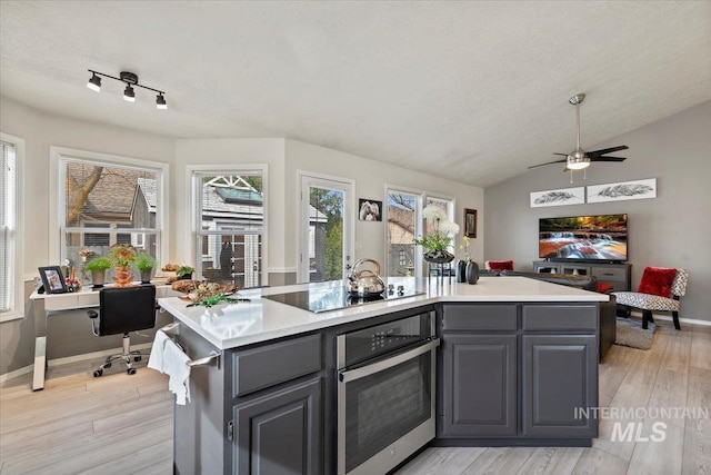 kitchen featuring light countertops, stainless steel oven, light wood-style flooring, gray cabinets, and black electric cooktop