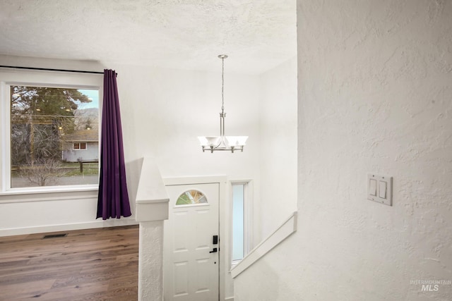 foyer entrance featuring hardwood / wood-style floors, a textured ceiling, and an inviting chandelier