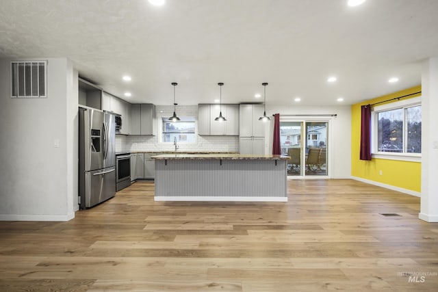 kitchen featuring light hardwood / wood-style floors, stainless steel appliances, decorative light fixtures, a center island, and gray cabinets