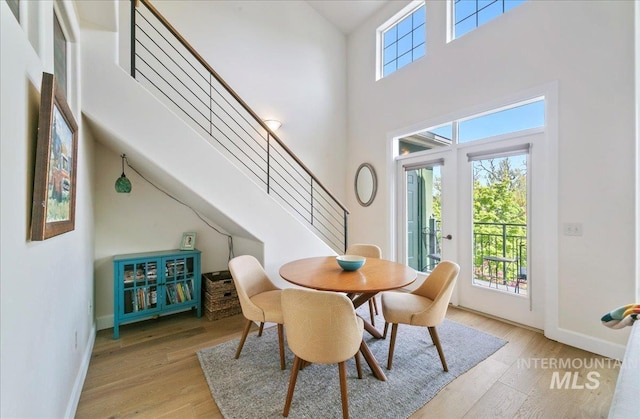 dining area with wood finished floors, baseboards, stairs, and a high ceiling
