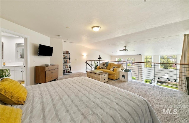 bedroom with baseboards, a textured ceiling, carpet, ensuite bath, and vaulted ceiling