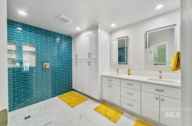bathroom with a sink, a tile shower, and tile walls